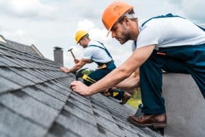 Selective Focus Of Handsome Handyman Repairing Roof With Coworker