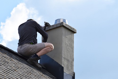 Roofer Construction Worker Repairing Chimney On Grey Slate Shingles Roof