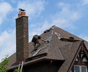 Roofer At Work Repairing A Steeply Sloped Shingle Roof